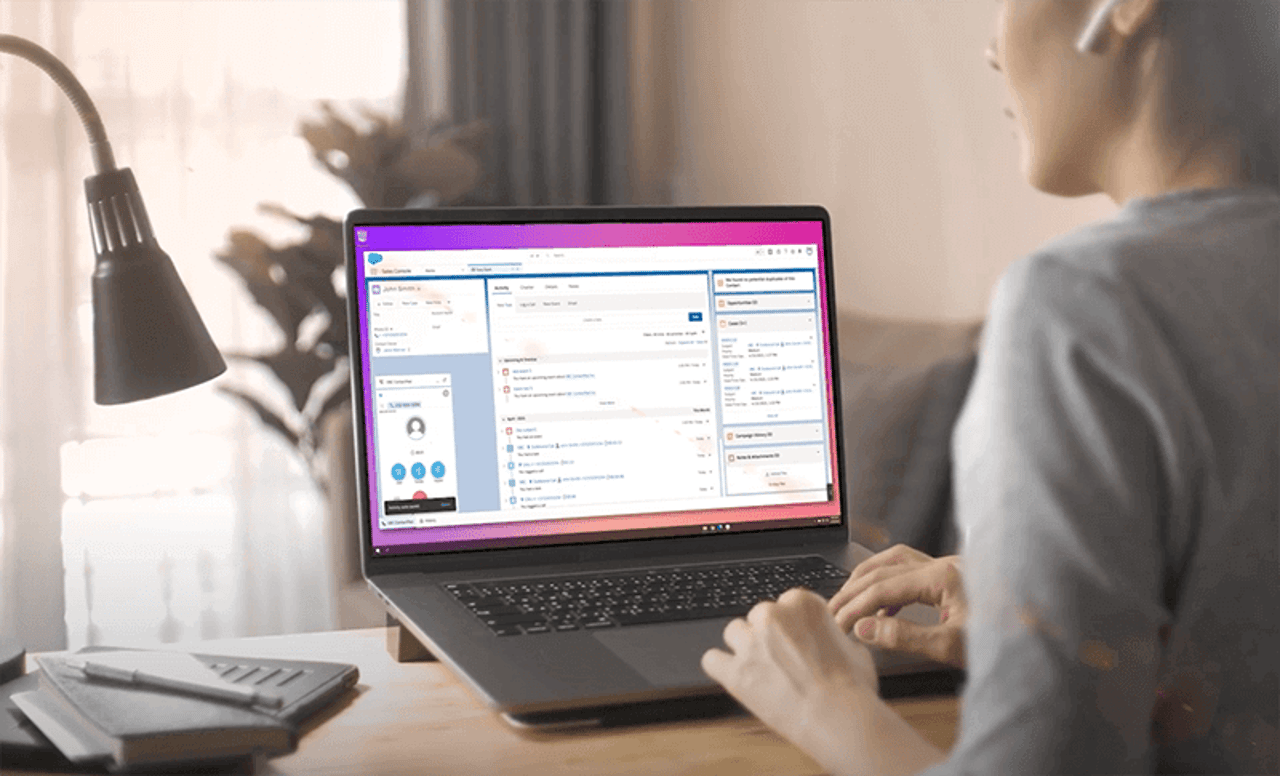 contact center agent at her desk with laptop open showing Vonage Business Communications embedded within Salesforce